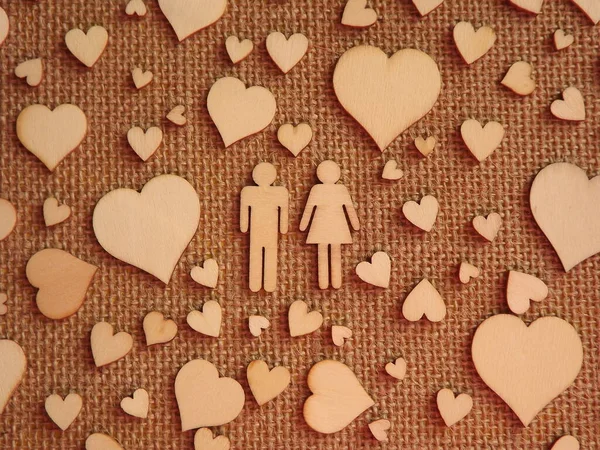 異なるサイズの木製の心とバレンタインデーカードとしてジュートファブリック上の男と女の人形。愛の宣言 — ストック写真