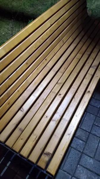A wooden bench in a night park in the evening in the rain close-up — Stock Photo, Image