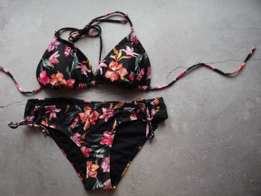 Gri bir arka planda siyah bikini mayo giymiş bir kadının çizimi.