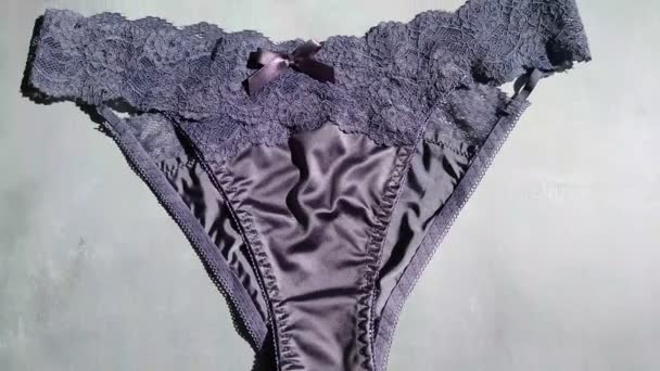 Bragas eróticas azules oscuras hechas de seda y guipure de cerca sobre un fondo gris — Vídeos de Stock