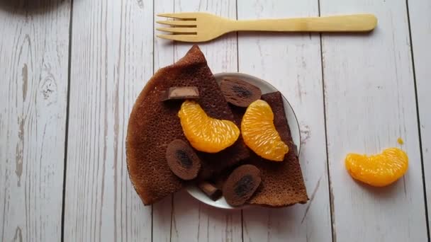 Csokoládés palacsinta csokoládés cukorkával és mandarin szeletekkel reggelire — Stock videók