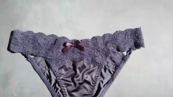 Dark blue erotic panties made of silk and guipure close-up on a gray background — Stock Video