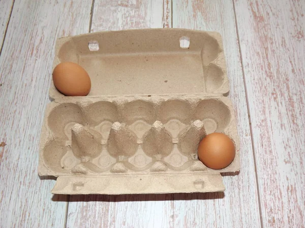 Uova di pollo beige in una scatola di uova su uno sfondo di legno chiaro — Foto Stock