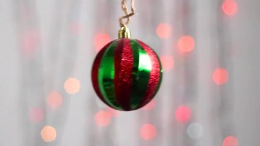 Güzel Noel ağacı oyuncağı çok renkli yılbaşı ışıklarının arka planında asılı duruyor. Yakın plan. Kırmızı-yeşil küre şeklinde Noel ağacı oyuncağı.