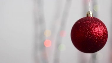 Güzel Noel ağacı oyuncağı çok renkli Noel ışıklarının arka planında asılı ve hafifçe hareket ediyor. Yakın plan. Noel ağacı oyuncağı kırmızı renkli bir küre şeklinde parlıyor.