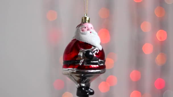漂亮的圣诞树玩具挂在五彩缤纷的圣诞彩灯的背景上 轻轻摇曳着 圣诞树上的玩具看起来像圣诞老人 — 图库视频影像