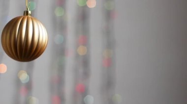 Güzel Noel ağacı oyuncağı çok renkli yılbaşı ışıklarının arka planında asılı duruyor. Yakın plan. Altın bir küre şeklinde Noel ağacı oyuncağı.