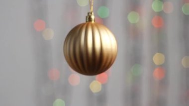 Güzel Noel ağacı oyuncağı çok renkli yılbaşı ışıklarının arka planında asılı duruyor. Yakın plan. Altın bir küre şeklinde Noel ağacı oyuncağı.