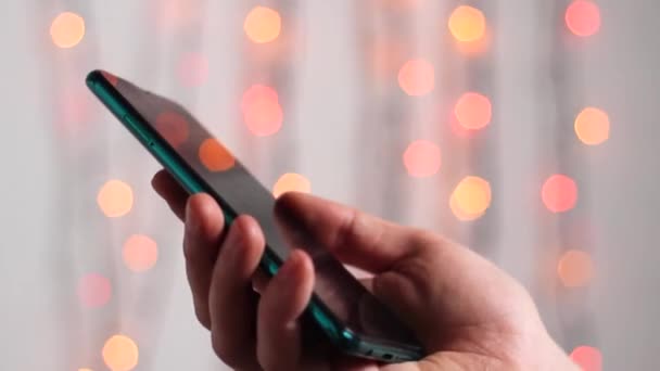 사람은 휴대폰으로 새해의 불빛을 배경으로 메시지를 입력하고 남자가 격리되어 전화로 — 비디오