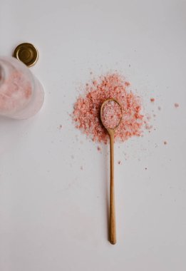 Tahta kaşıkla beyaz masada pembe tuz.