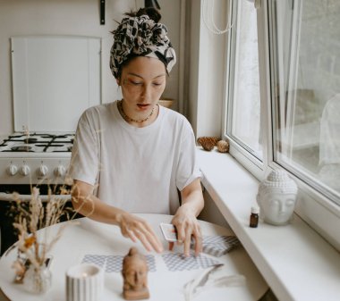 Beyaz mutfakta tarot kartları olan kadın.