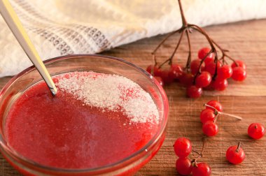 Tahta masadaki cam vazoda şekerli viburnum zemininden kırmızı böğürtlen. Vitamin tatlılığı.