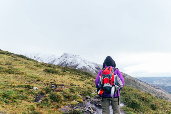 unrecognizable person doing a mountain route. He carries a backpack with utensils, to eat, drink and drink coffee. take clothes for the cold. hiking up the mountain to the snowy summit.