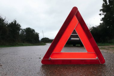 Red triangle of a car on the road. Car warning triangle. Car breakdown in bad weather. clipart