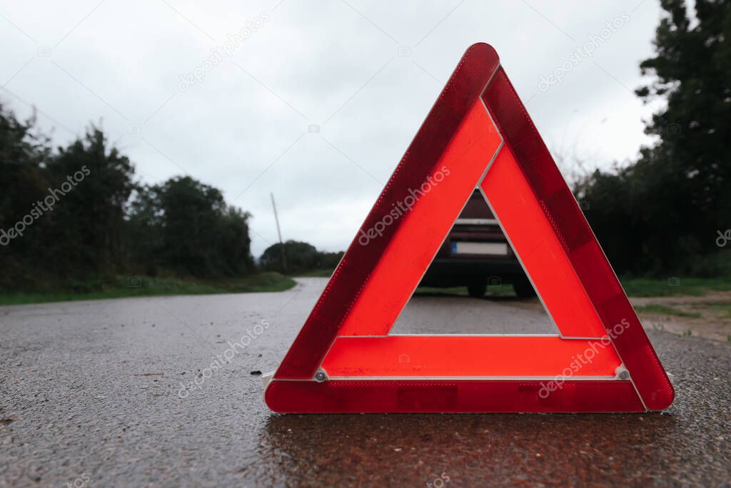 Red triangle of a car on the road. Car warning triangle. Car breakdown in bad weather.