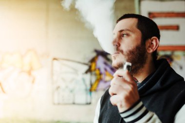 Sigara içme terapisi için elektronik sigarasını kullanan bir adam. Tütüne alternatif olarak. Genç adam buhar yapıyor. tütünü bırak