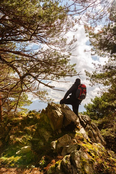 unrecognizable hiker with red backpack stands on a rock contemplating the mountainous landscape. person taking a break. mountain activities. weekend getaway.