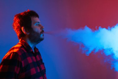 Renkli ışıkların arasındaki adam büyük bir buhar bulutunu buharlaştırıp üfledi. Sigara içmeyi bırakmak için elektronik sigara kullanan bir çocuk..