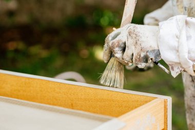 Ahşap bir mobilyaya boya ve ağda uygulayan kirli eldivenli el yazısı. Mobilya restorasyonu.