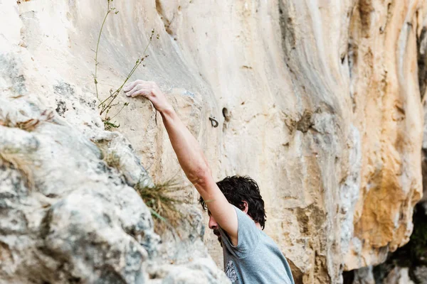 Man climbing a mountain and holding onto the rock with his hand. extreme sports and mountains.