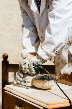Tahta yüzeyde elektrikli zımpara makinesi kullanan tanınmayan biri. Kopyalama alanı olan dikey fotoğrafçılık.