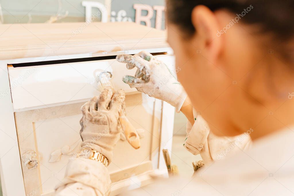 Unrecognizable person painting an old wooden furniture with a brush. Woman restoring a piece of furniture