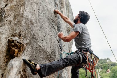 Genç adam tırmanıyor ve dağdaki zor bir engeli aşıyor. risk sporu ve dağ.