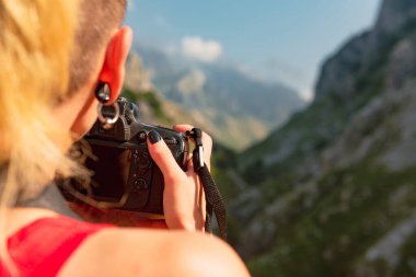 Bilinmeyen kişi bir kamera tutuyor ve dağ geçidini çekiyor. Yürüyüşçü fotoğraf çekiyor.