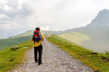 Sırt çantasıyla dağda yürüyüş yapan genç adam.