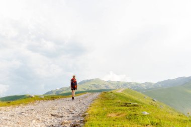 Sırt çantasıyla dağda yürüyüş yapan genç bir kadın.