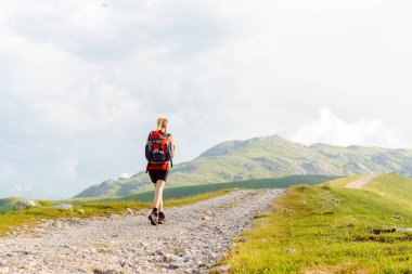 Sırt çantasıyla dağda yürüyüş yapan genç bir kadın.