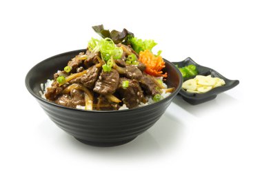 Biftek BBQ Bulgogi Kore yemeği pilav tarifinde kızartılmış acı biber ve sarımsaklı sebzeler servis edilir.