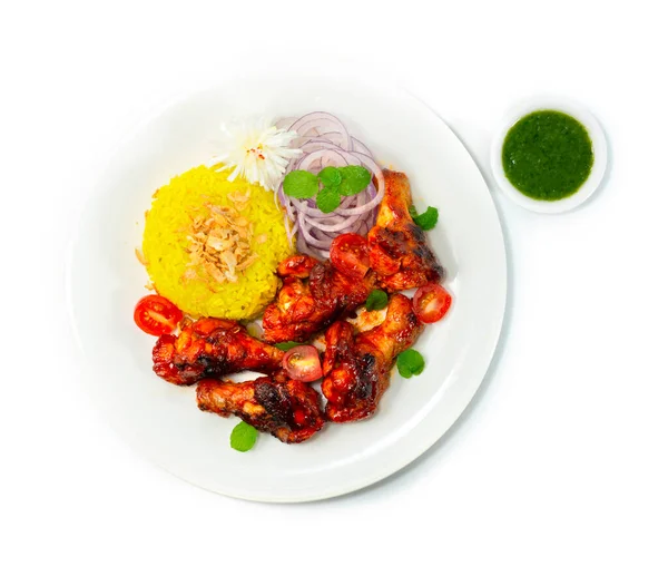 Tandoori Chicken Grilled served Mint Sauce and Biryani Rice recipe ontop Crispy Onion is a classic Indian dinner that marinates chicken wing in a creamy yogurt base, blended spice decorate with Onion topview