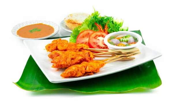 Spicy Chicken Satay or Spicy Grilled Chicken in Skewers served Grilled Bread dipping chili peanut Sauce, Sweet and Sour Sauce Thai Food appetizer dish decoration with carving vegetables sideview