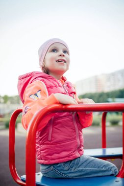 Ceketli bir kız atlıkarıncaya oturur ve kafasını kaldırır.