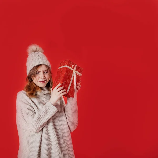 Dreaming zima dziewczyna gospodarstwa Boże Narodzenie obecny na czerwonym tle — Zdjęcie stockowe