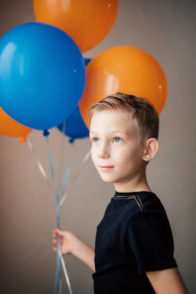 Un chico de aspecto europeo en una camiseta negra se para con globos. —  Fotos de Stock