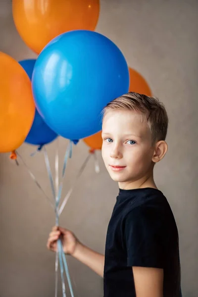 Un chico de aspecto europeo en una camiseta negra se para con globos. —  Fotos de Stock