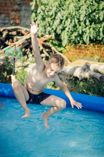 Blonďatý chlapec skákání do nafukovacího bazénu — Stock fotografie