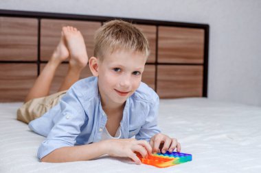 Çocuk elinde bir Pop It oyuncağı tutuyor. Stres önleyici baloncuklu esnek dokunsal oyuncak