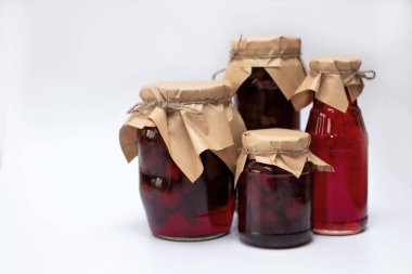 Çilek şurubuyla farklı şekillerde kavanozlar ve beyaz bir tabakta reçel..