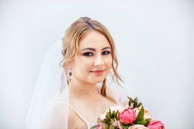 Gelinlikli esmer kız. Elinde buket olan beyaz elbiseli bir gelin. Makyaj.