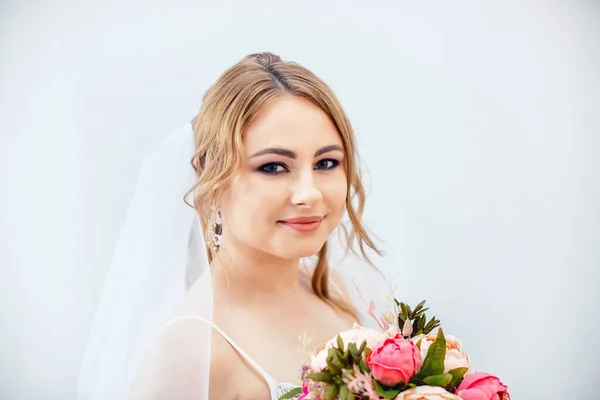 Menina morena em um vestido de noiva. Noiva em um vestido branco com um buquê nas mãos. Maquiagem. — Fotografia de Stock