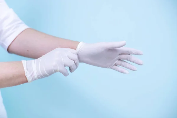 Médecins mains dans des gants médicaux sur un fond turquoise — Photo