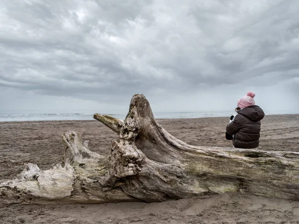 Paesaggio Una Spiaggia Invernale Con Bambina Seduta Tronco Albero — Foto Stock