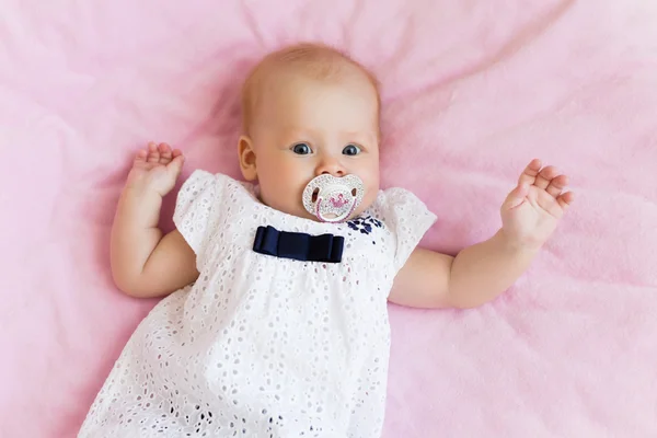 ピンクの背景のおしゃぶりの美しい子供 — ストック写真