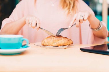 Kafenin terasında kruvasan kesen bir kadın..