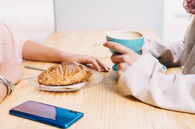 Kafeteryanın terasında kahvaltı yapan iki kızın ellerinin ayrıntıları..