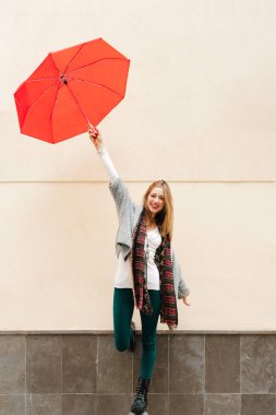 Güzel sarışın kız kırmızı bir şemsiye tutuyor.