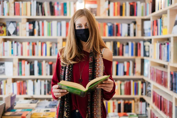 Όμορφη Ξανθιά Γυναίκα Φορώντας Μάσκα Προσώπου Ένα Βιβλίο Ένα Βιβλιοπωλείο — Φωτογραφία Αρχείου